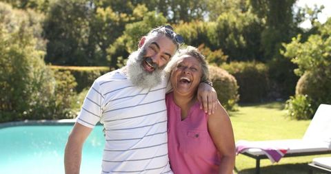 Happy Senior Friends Laughing by Sunlit Poolside