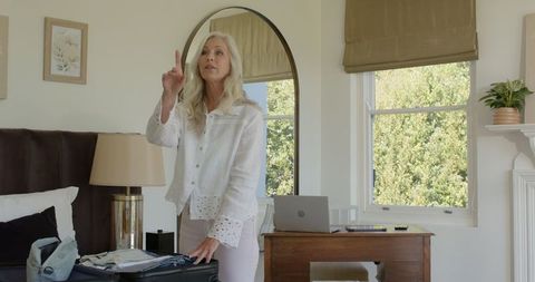 Senior Woman Packing Suitcase for Travel with Focused Expression