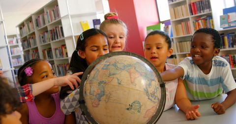 Diverse children exploring globe in school library