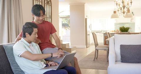 Father and Teenage Son Bonding Over Laptop at Home Living Room