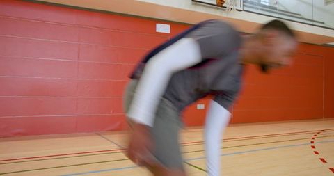 Male athlete sprinting on indoor basketball court with motion blur and training drill