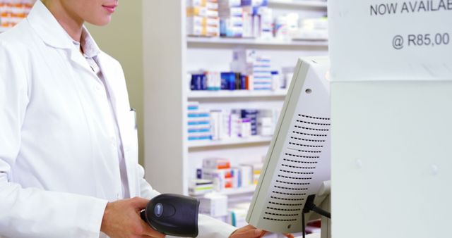 Smiling pharmacist holding barcode scanner in pharmacy
