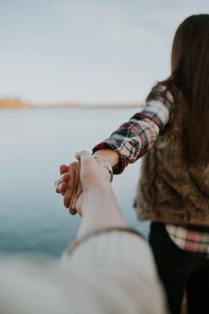 Couple holding hands by lakeside showing love and bonding. Perfect for use in romantic, relationship, social media posts, and promotional materials for couples therapy or relationship advice. Ideal for illustrating themes of affection, connection, and intimacy.