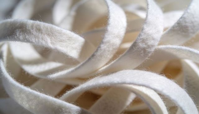 Soft white felt ribbon loops macro abstract texture with tangled fibers and bokeh
