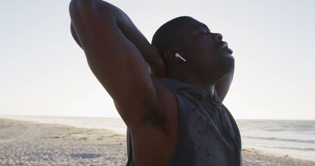 Man stretching with earbuds after beach workout at sunrise - Download Free Stock Images Pikwizard.com