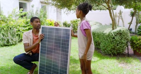 Father and Daughter Inspecting Solar Panel in Garden