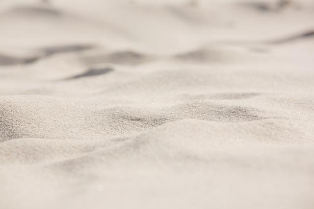 Close-up view of sand surface at beach, showcasing fine granular texture and natural patterns. Ideal for use in travel brochures, summer vacation promotions, nature backgrounds, and environmental awareness campaigns.