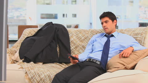 Businessman Relaxing on Couch Watching TV After Work
