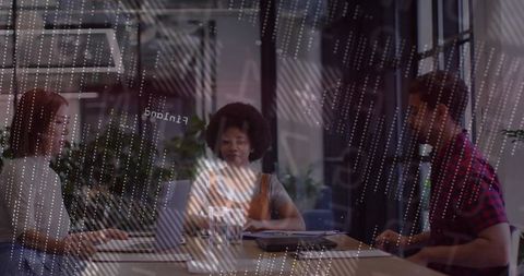 Leading woman reviewing laptop and documents with team in glass conference room bright