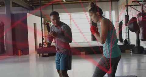 Coach guiding boxer through drills in industrial warehouse gym during daylight training