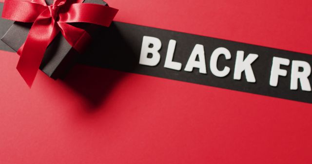 Black friday text in white on black stripe and black gift box with red ribbon, on red background. Luxury treat, present, shopping, black friday sale and retail concept digitally generated image.