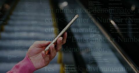 Hands holding smartphone on escalator with transparent code overlay