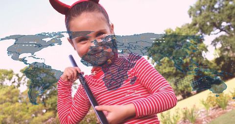 Playful girl wearing horn headband holding stick exploring holographic world map outdoors