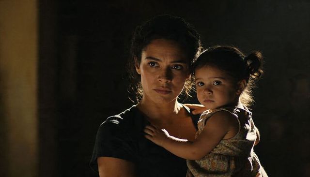 Mother holding toddler with rim lighting, intimate moody family portrait showing protection
