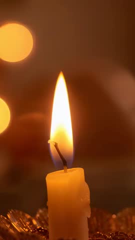 Vertical clip of yellow candle flame flickering closeup with wax drips and warm bokeh glow