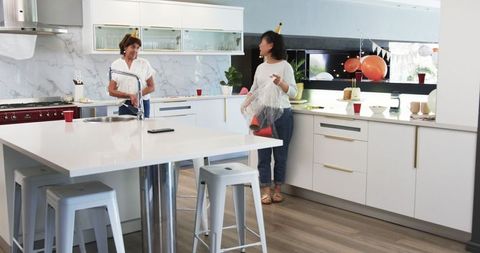 Senior Friends Tidying Up After Lively Birthday Celebration