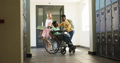 Multicultural teens assisting wheelchair classmate in school hallway promoting inclusion