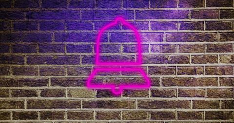 Neon bell sign glowing on brick wall in urban nightlife scene