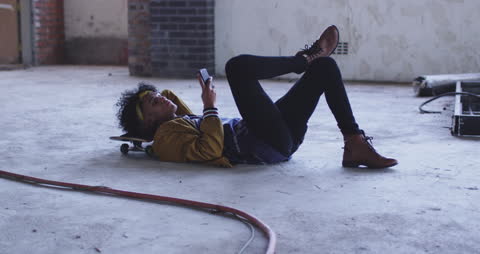 Young Man Lying on Skateboard Using Smartphone