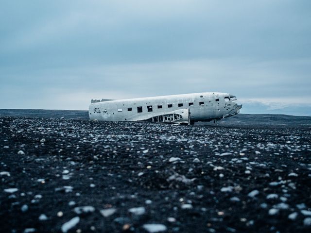 Dramatic scene shows abandoned airplane wreck on a black sand beach under an overcast sky. Stark contrast enhances feeling of desolation and solitude. Ideal for topics related to abandonment, history, exploration, adventure, extreme terrain, and travel destinations like Iceland.
