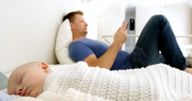 Father Relaxing on Bed while Baby Sleeps Near Him - Download Free Stock Images Pikwizard.com