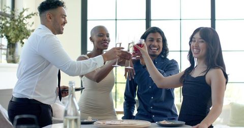 Friends toasting at chic sunlit celebration in contemporary lounge