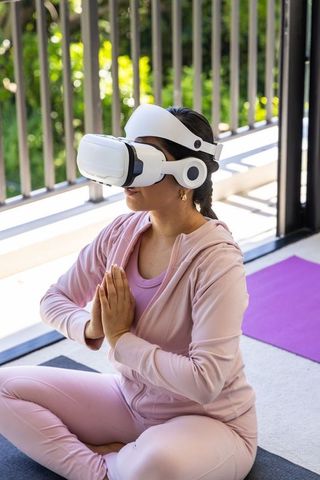 Woman meditating with vr headset on sunny balcony yoga mat for mindfulness and vr wellness