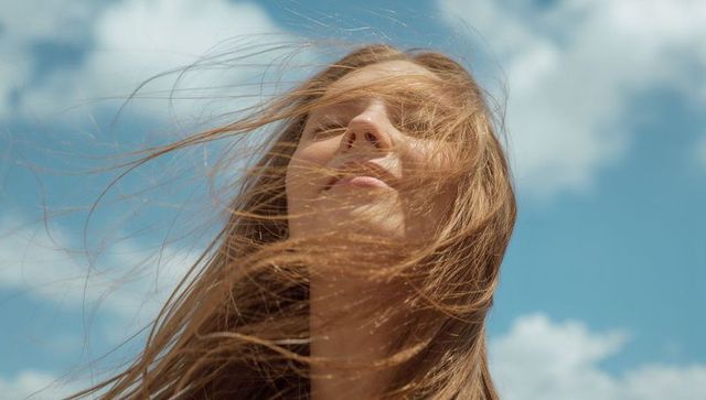 Serenity and Freedom: Woman Embracing Wind Beneath Blue Sky