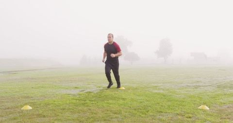 Determined Man Jogging on Misty Field Checking Progress