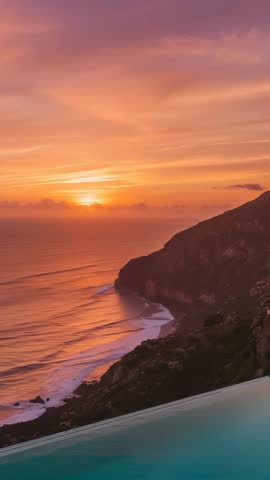 Vertical sunset over cliffside infinity pool mirroring clouds and ocean waves
