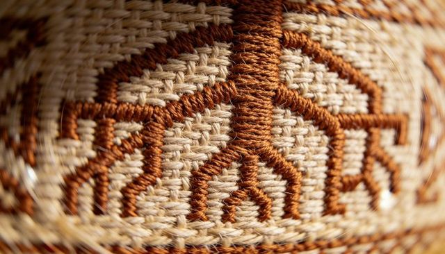 Close-up woven fiber panel with brown embroidered branch motif macro textile texture