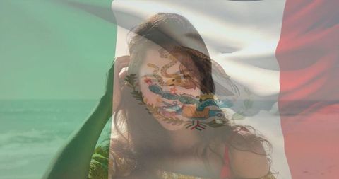 Woman standing at shore touching hair in yellow off-shoulder top with mexican flag double exposure
