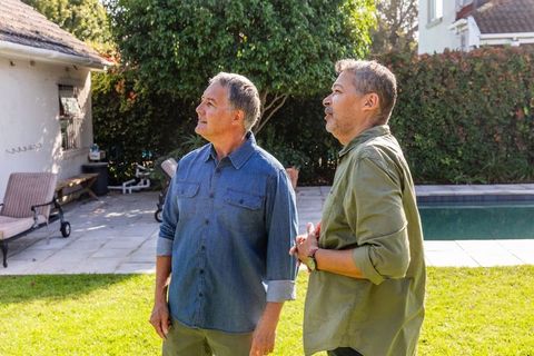 Senior male friends enjoying sunny backyard retreat