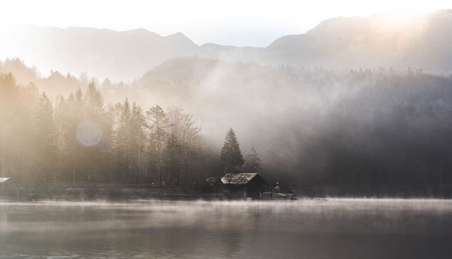 This image of a serene and foggy morning at a lake with a mountainous backdrop can be used for promoting tranquility and solitude in a natural setting. Perfect for backgrounds, travel brochures, relaxation themes, and environmental campaigns.