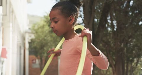 Child Playing with Hula Hoop Outdoors in Sunny Backyard