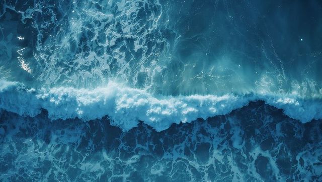 Aerial view of ocean waves with luminous aqua foam patterns