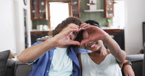 Romantic Young Couple Forming Heart Pose in Cozy Living Room