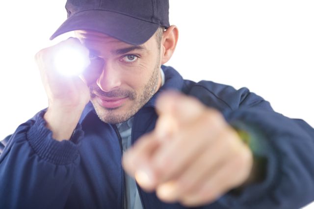 Close-up of security officer holding a torch against white background