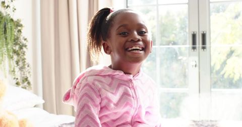 Happy Child in Cozy Pink Robe Enjoying Sunlight