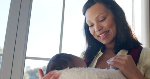 Woman cradling infant by sunlit window for bonding moment