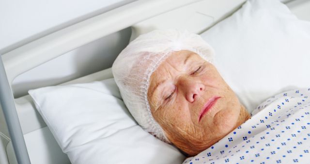 Senior woman resting peacefully in hospital bed wearing protective hair cap and medical gown. Useful for illustrating hospital patient care, elderly healthcare services, medical treatment recovery, and hospital environments.