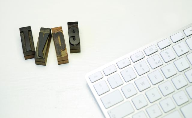 Vintage printing blocks spelling 'type' next to a sleek modern keyboard. This juxtaposition highlights the evolution from traditional printing methods to contemporary digital technology. Ideal for use in articles or presentations on typography history, graphic design, or the progression of writing tools.