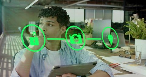 Young man holding tablet visualizing ar icons for security, media, innovation in office