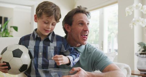 Father and son watching sports at home sharing quality time