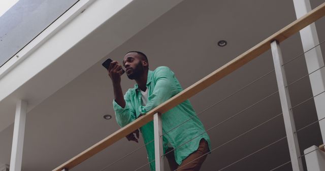 Man Leaning Against Railing Looking at Smartphone Indoors - Download Free Stock Images Pikwizard.com