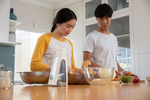 Young Couple Preparing Fresh Vegetable Salad in Modern Kitchen