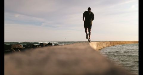 Man Jogging on Seawall by Ocean during Sunset - Download Free Stock Images Pikwizard.com