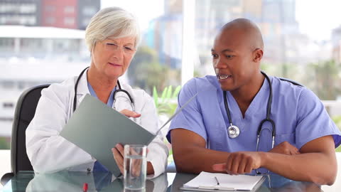 Smiling Doctors Discussing Patient Documentation in Modern Office