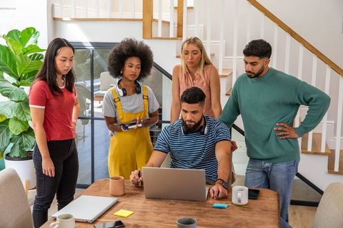 Diverse Team Collaborating Around Laptop in Loft Space