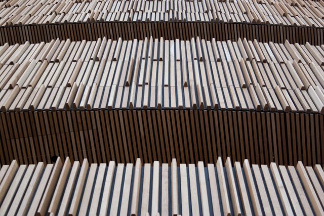 Abstract close-up of overlapping wooden slats forming a repetitive pattern. Useful for backgrounds, design inspiration, architectural concepts, or construction advertisements.